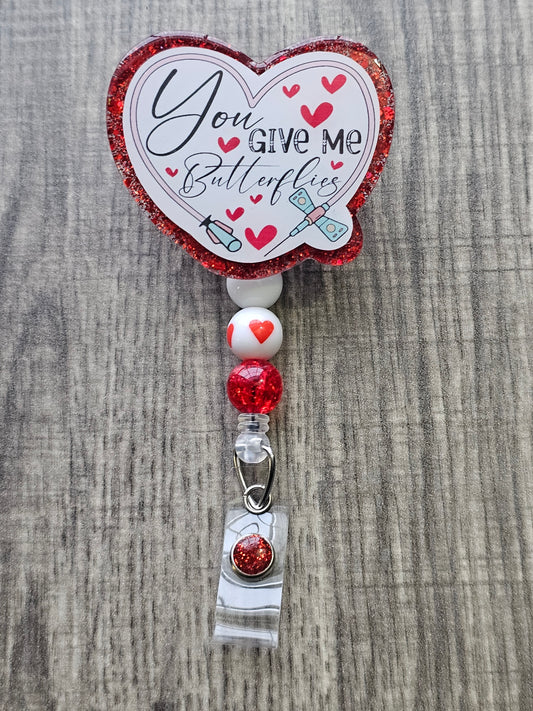 A Badge Reel stating 'You give me butterflies' shaped in the form of a heart, surrounded by a butterfly needle in support of lab techs.