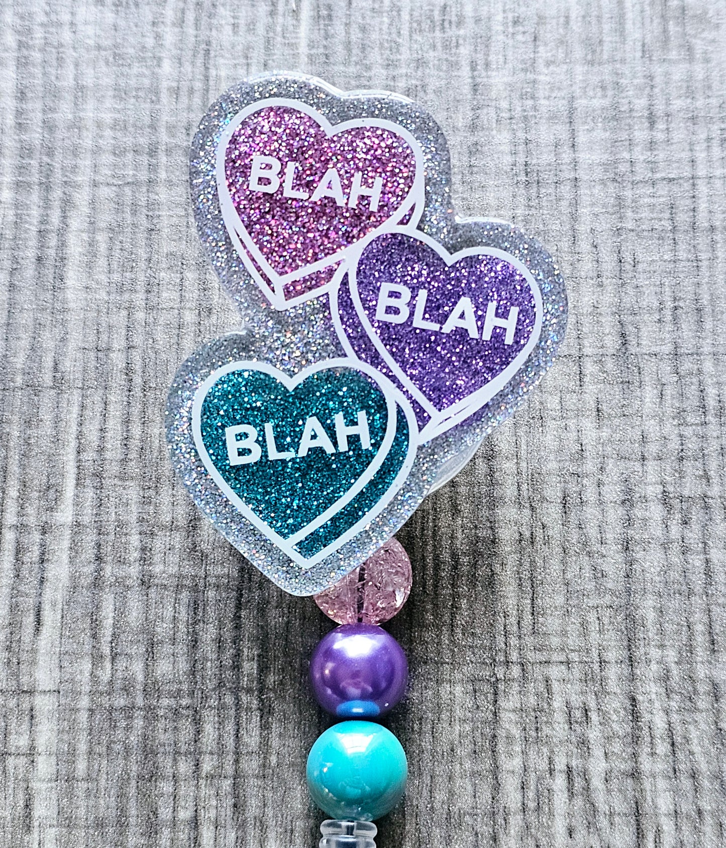 A badge reel featuring three ascending hearts in vibrant colors, each heart playfully displays the word “blah” in bold lettering.